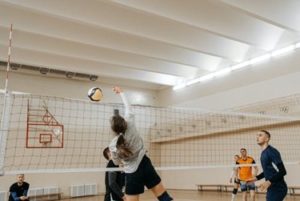 A girl hitting the ball across the net during a volleyball match